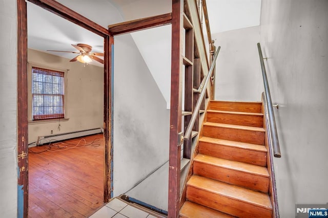 stairway featuring hardwood / wood-style floors, a ceiling fan, and a baseboard radiator