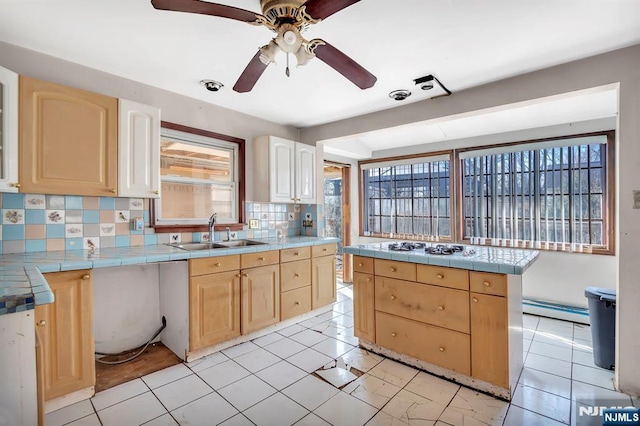 kitchen with tile counters, tasteful backsplash, baseboard heating, and a sink