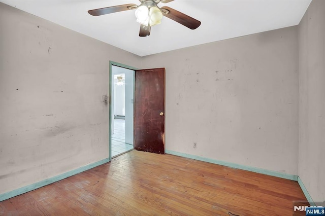 unfurnished room featuring ceiling fan, baseboards, and hardwood / wood-style floors