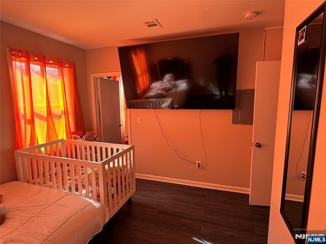 bedroom with electric panel, wood finished floors, visible vents, and baseboards