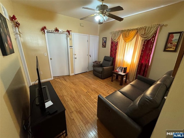 living area with hardwood / wood-style flooring and a ceiling fan