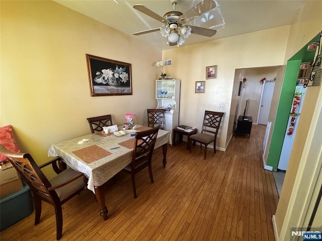 dining room with hardwood / wood-style floors, visible vents, baseboards, and ceiling fan