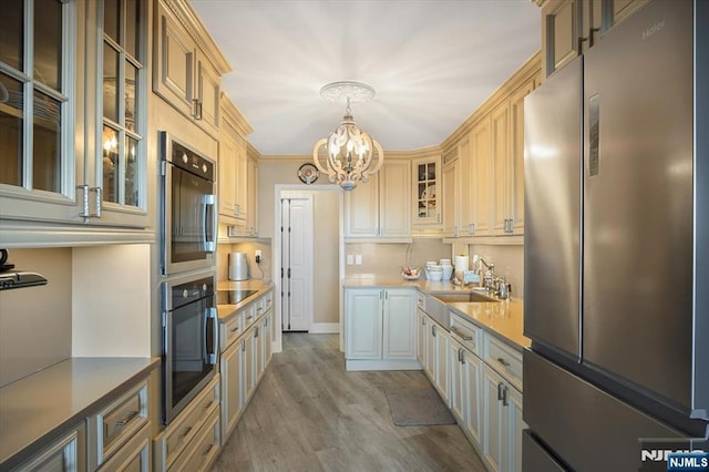 kitchen with light wood-style flooring, a sink, light countertops, appliances with stainless steel finishes, and a chandelier