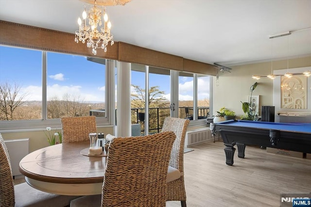 interior space with plenty of natural light, an inviting chandelier, wood finished floors, and pool table