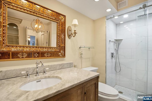 bathroom with vanity, toilet, visible vents, and a tile shower