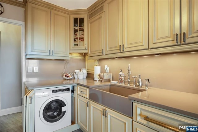 laundry area featuring light wood finished floors, baseboards, washer / dryer, cabinet space, and a sink