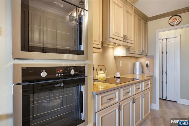 kitchen featuring crown molding, baseboards, light countertops, light wood-style flooring, and black appliances