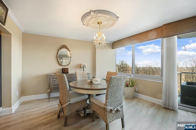 dining space featuring a chandelier, light wood-style flooring, baseboards, and ornamental molding