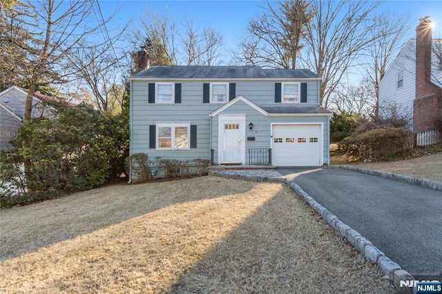 view of front of home featuring a front lawn, a garage, driveway, and a chimney