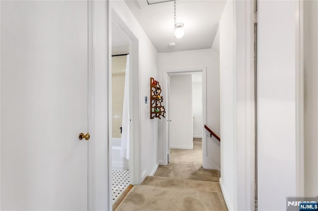 hall featuring an upstairs landing and light colored carpet