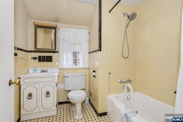 full bathroom with wallpapered walls, toilet, vanity, shower / bathtub combination, and tile walls