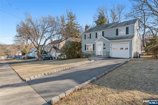 view of front of home with a garage, driveway, and a chimney