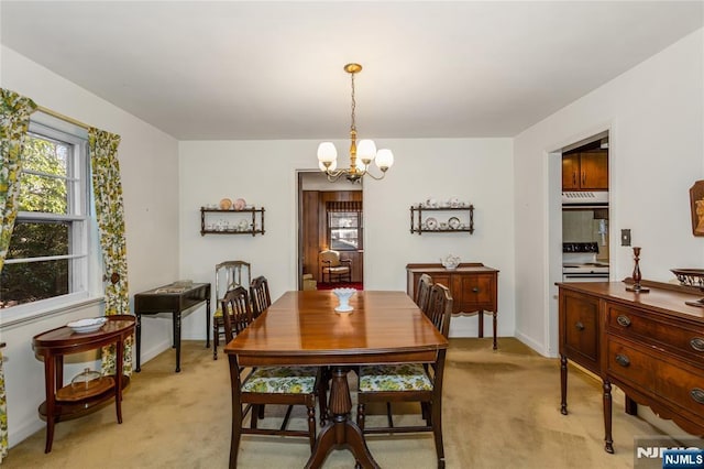 dining area featuring baseboards, light carpet, and a notable chandelier