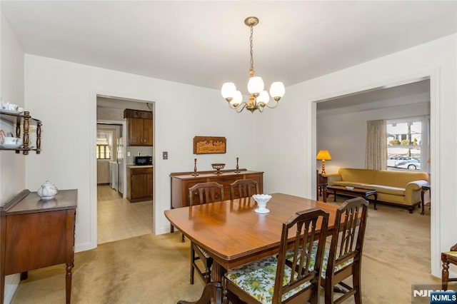 dining area with a notable chandelier and light carpet