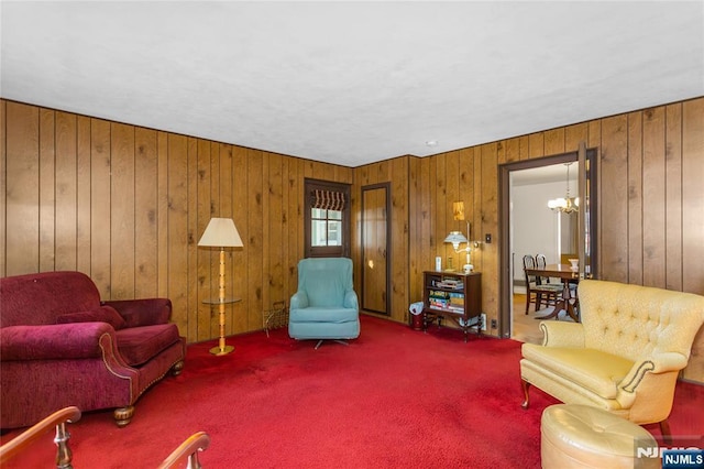 carpeted living room featuring wooden walls and an inviting chandelier