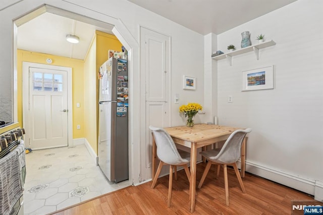 dining room featuring arched walkways, baseboards, and light wood-style floors