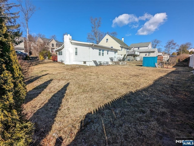 rear view of house with a yard, fence, and a chimney