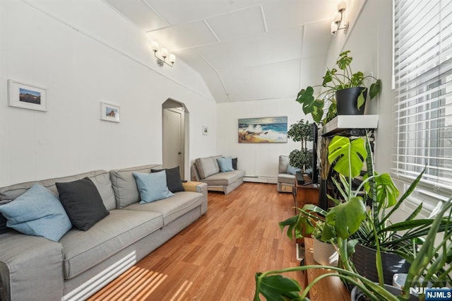 living room with light wood-type flooring, arched walkways, lofted ceiling, and a healthy amount of sunlight