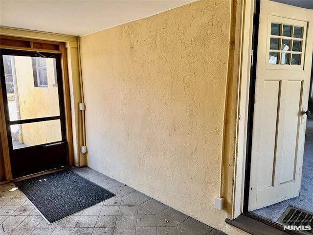 entrance to property with visible vents and stucco siding