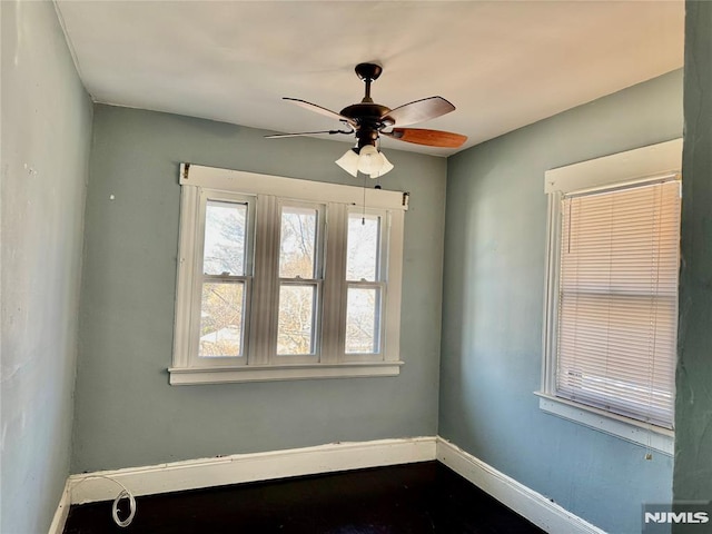 empty room with a ceiling fan and baseboards