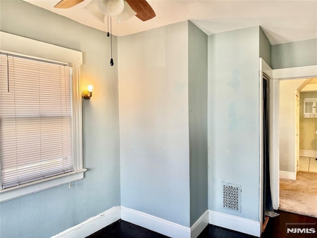 empty room featuring a ceiling fan, visible vents, and baseboards