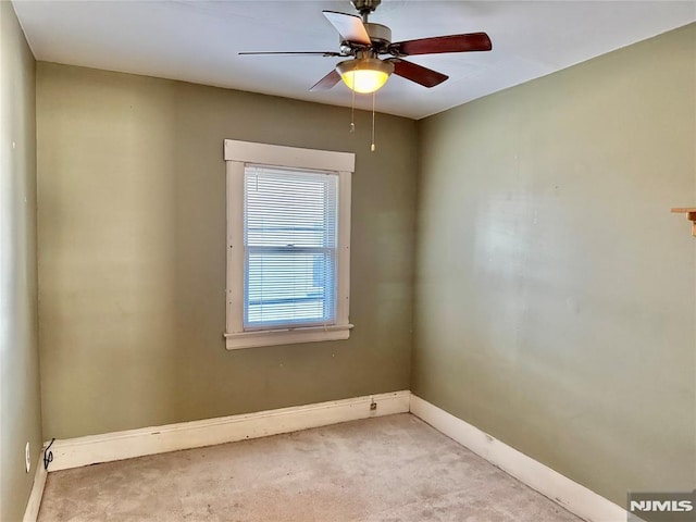 carpeted spare room featuring baseboards and a ceiling fan