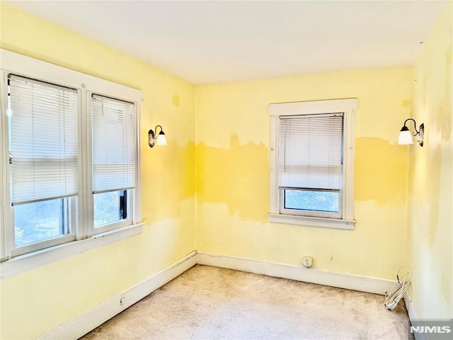 spare room featuring light colored carpet, baseboards, and a baseboard radiator