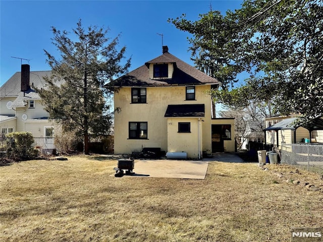 back of property with stucco siding, fence, a yard, roof with shingles, and a patio area