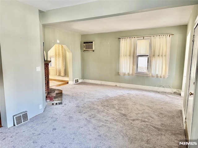 carpeted spare room with visible vents, baseboards, and a wall unit AC