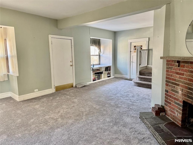 unfurnished living room featuring stairway, carpet flooring, a fireplace, and baseboards