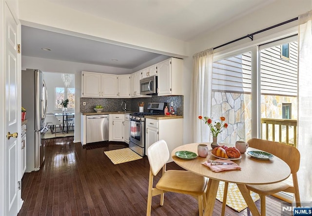 kitchen with dark wood-style floors, decorative backsplash, white cabinets, and stainless steel appliances