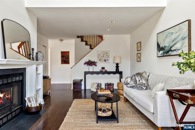 living room with stairway, a fireplace with flush hearth, and wood finished floors