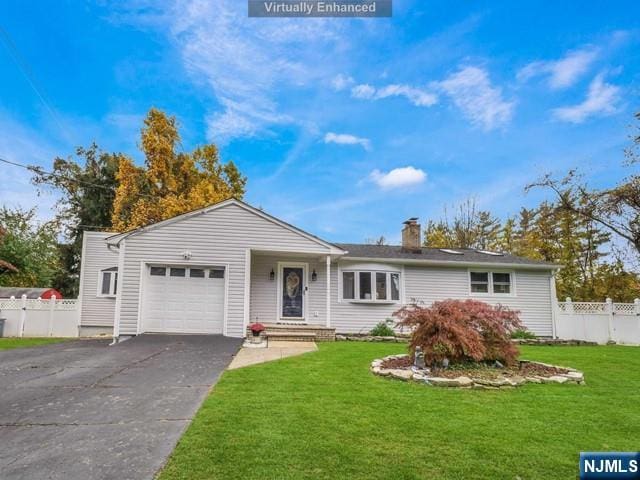 ranch-style house featuring a front yard, fence, driveway, an attached garage, and a chimney