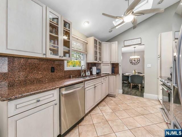 kitchen with ceiling fan with notable chandelier, a sink, backsplash, appliances with stainless steel finishes, and light tile patterned flooring