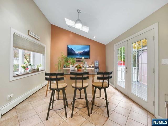 dining room with light tile patterned floors, a healthy amount of sunlight, french doors, and a baseboard heating unit