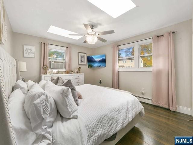 bedroom with cooling unit, a ceiling fan, baseboards, dark wood finished floors, and a skylight