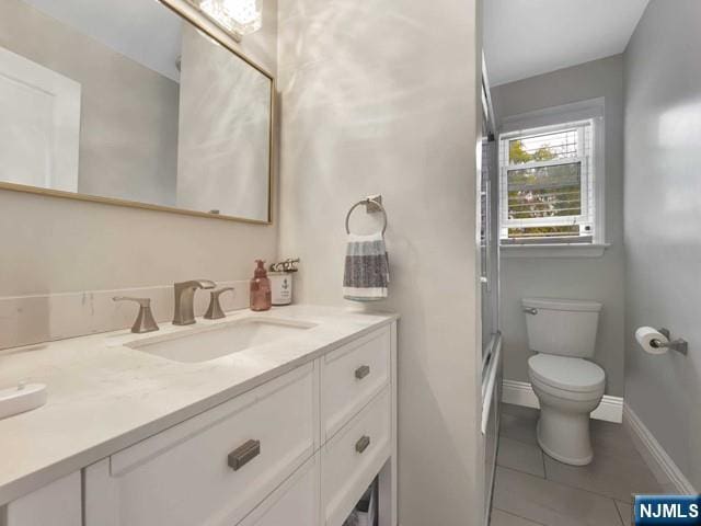 full bathroom with vanity, baseboards, tile patterned floors, toilet, and a shower with door