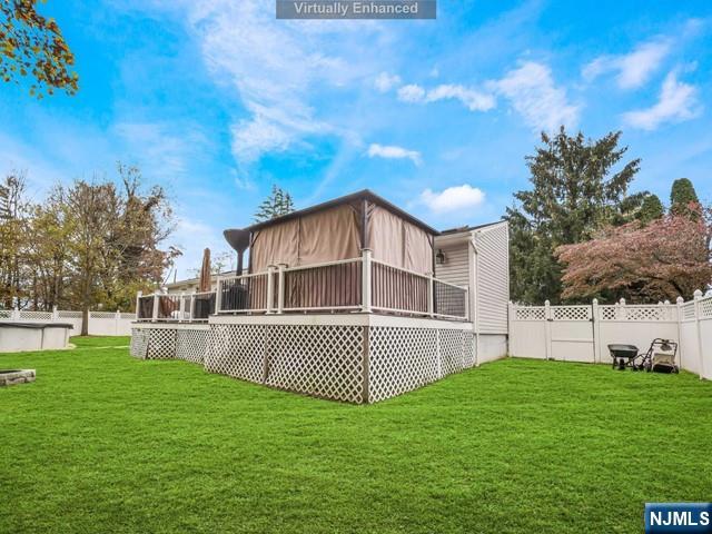 rear view of house with a lawn, a wooden deck, and a fenced backyard