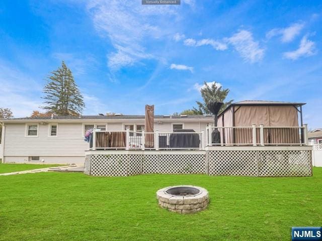 rear view of house featuring a deck, a yard, and an outdoor fire pit