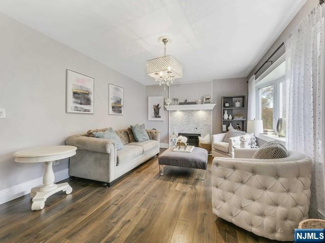 living area featuring a fireplace, baseboards, an inviting chandelier, and wood finished floors