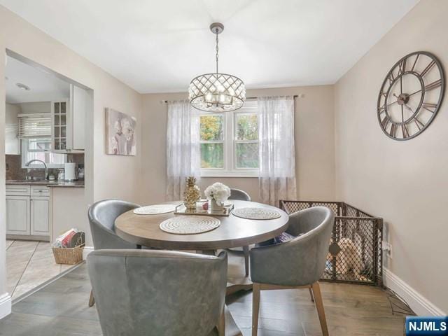 dining area with an inviting chandelier, baseboards, and light wood-type flooring