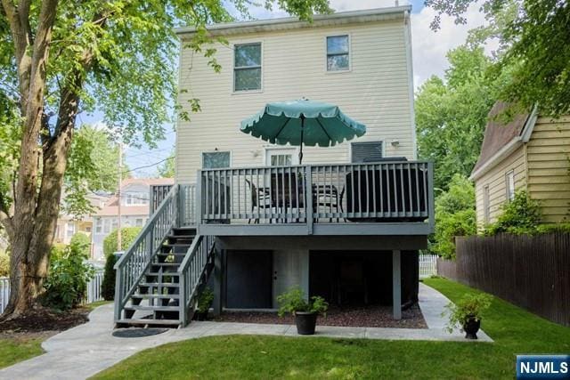 rear view of house featuring a lawn, a deck, stairs, and fence