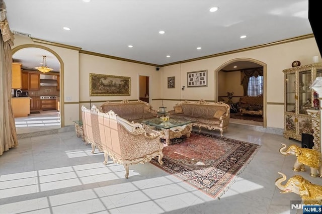 living area with recessed lighting, arched walkways, marble finish floor, and ornamental molding