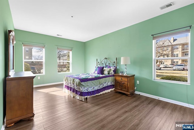 bedroom featuring visible vents, baseboards, and wood finished floors