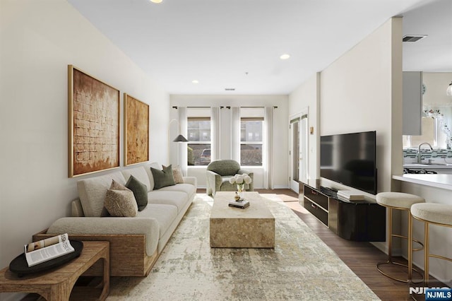 living room with visible vents, recessed lighting, and wood finished floors