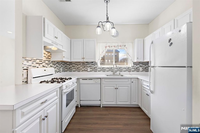 kitchen featuring under cabinet range hood, a sink, dark wood-style floors, white cabinetry, and white appliances