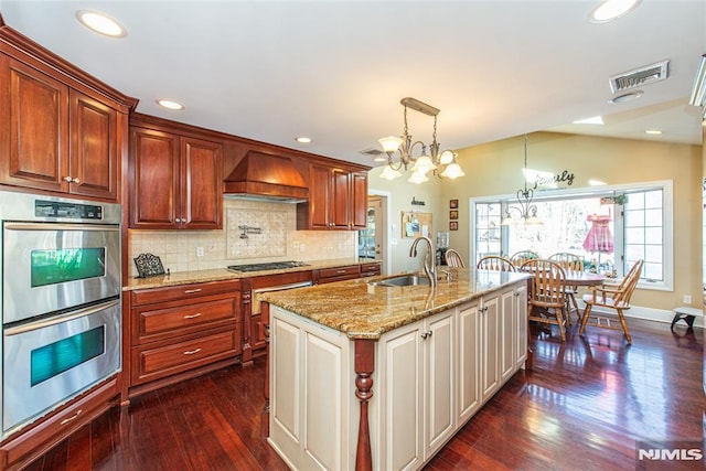 kitchen featuring premium range hood, visible vents, a sink, gas cooktop, and double oven