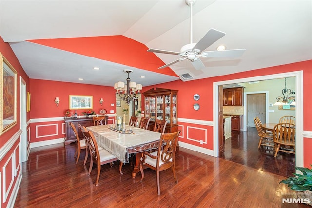 dining space featuring visible vents, dark wood-type flooring, lofted ceiling, wainscoting, and a decorative wall