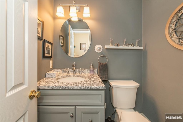 half bath featuring toilet, a chandelier, and vanity