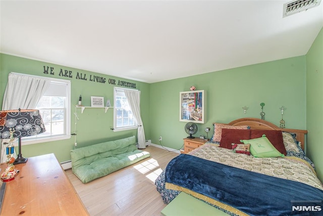 bedroom with visible vents, baseboards, wood finished floors, and a baseboard radiator